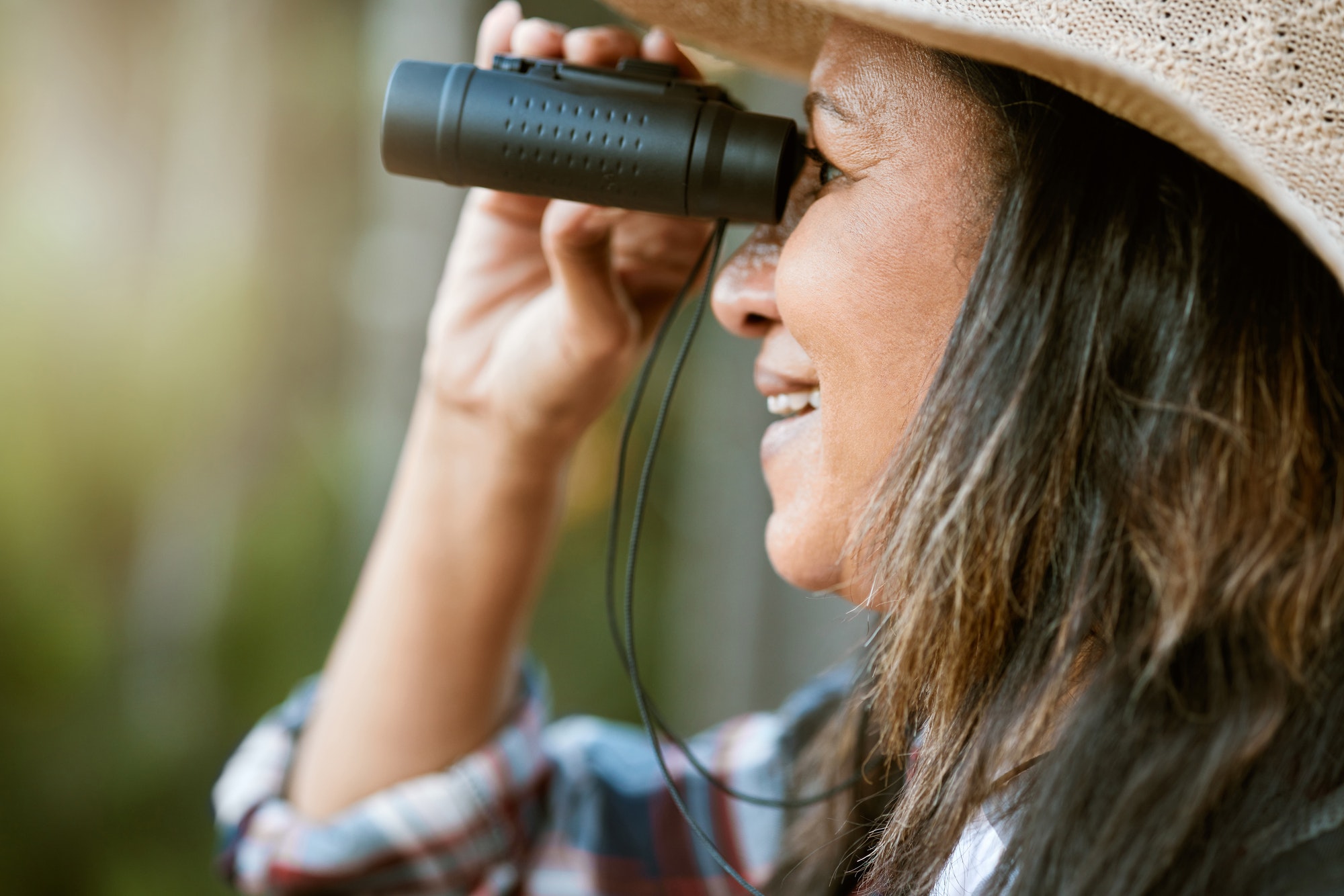 Nature, animal and bird watching of a smiling older woman looking and holding binoculars outside. C